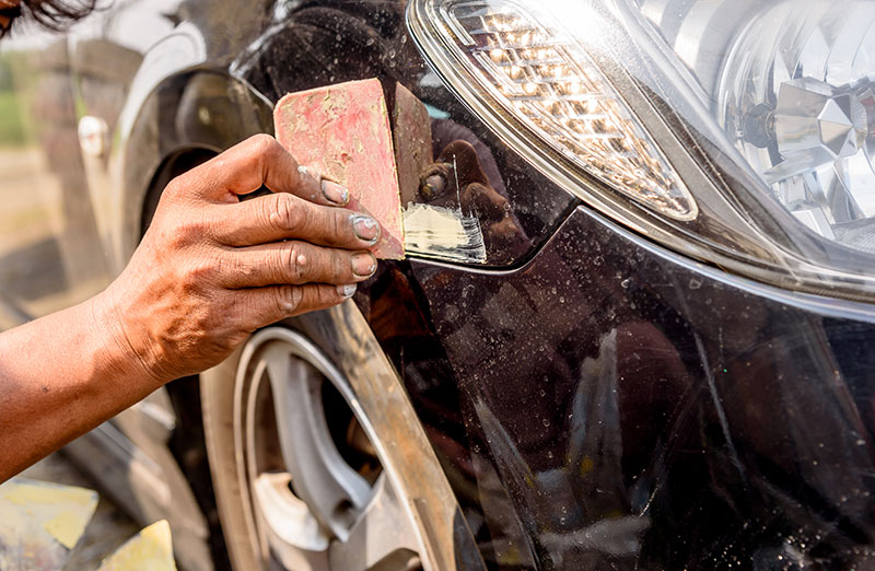 Close-up of man who is applying protective wax to a car bumper